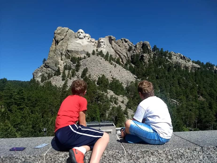 kids sitting on ledge looking at Mount Rushmore in South Dakota