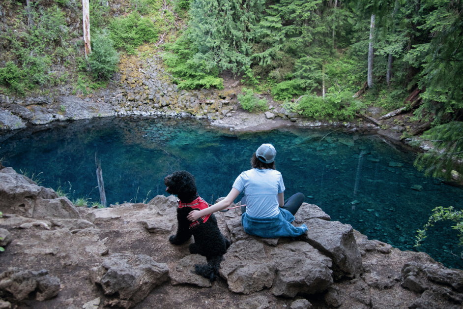 hiker and dog sitting at Tamolitch Blue Pool in Oregon 