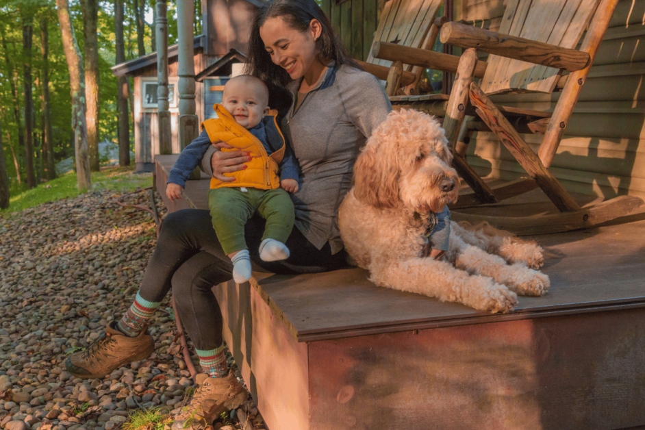 women, baby, and dog siting on porch while glamping in maryland