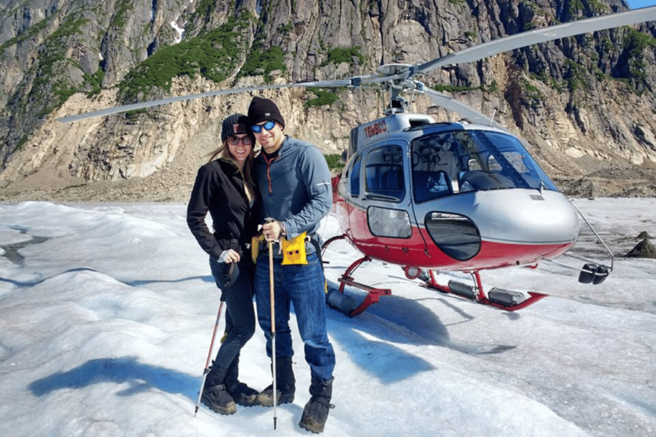 two people on honeymoon in alaska in front of a helicopter 