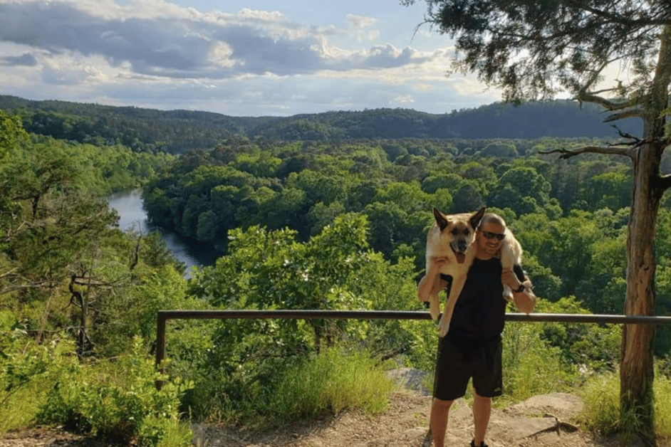 Man holding dog on shoulders on a hike in Broken Bow, OK. 