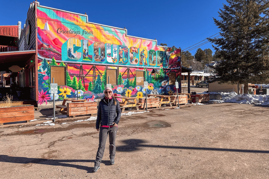 girl standing in front of colorful Welcome to Cloudcroft mural. 
