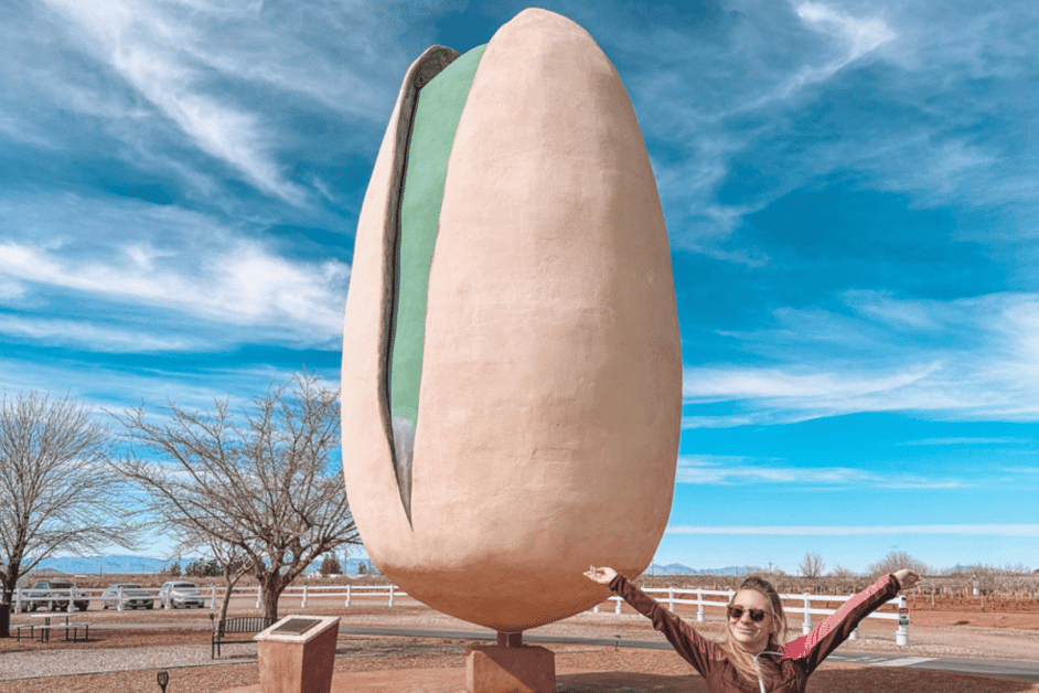 girl standing by the biggest pistachio in the world. 