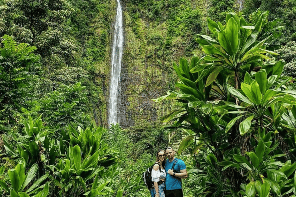 couple in front of waterfall on the road to hana pipiwai trail. 