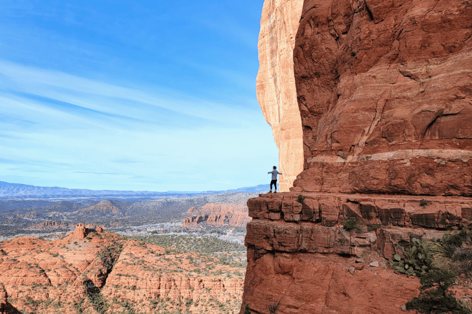 person standing at top of cathedral rock during one day in sedona. 