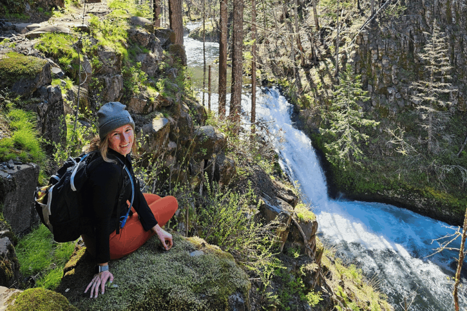 girl sitting by waterfall on tunnel falls hike. 