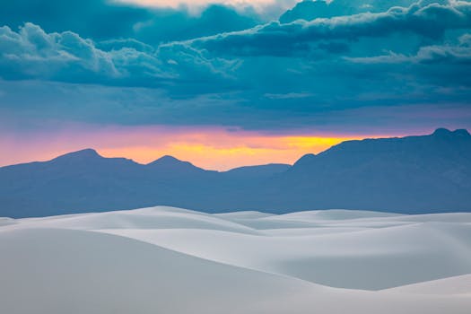 Stunning view of White Sands dunes at sunset with dramatic mountain backdrop.
