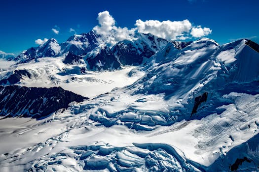 A stunning aerial shot of snow-covered mountains under a clear blue sky, showcasing nature's beauty.
