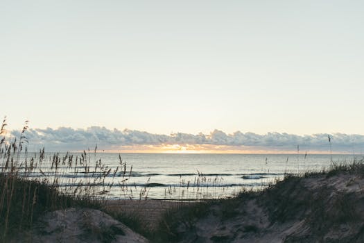 Serene sunset over sands and sea at Avon Beach, NC, tranquil and picturesque.