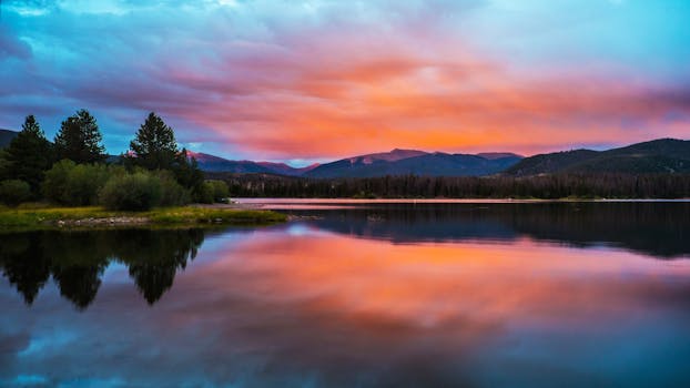 Tranquil sunset over Breckenridge lake with vivid sky and mountain reflections.