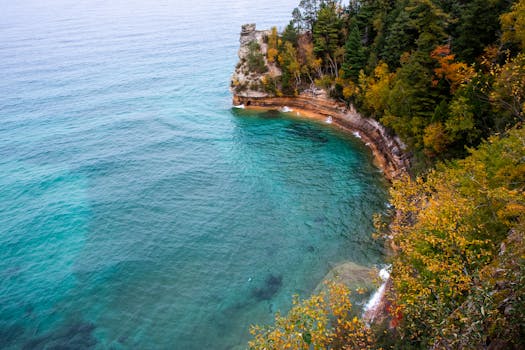 Experience the stunning cliffs and clear blue waters of Munising, Michigan, in this breathtaking aerial shot.
