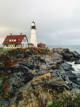 Scenic view of Portland Head Light in Maine against dramatic rocky cliffs and ocean.