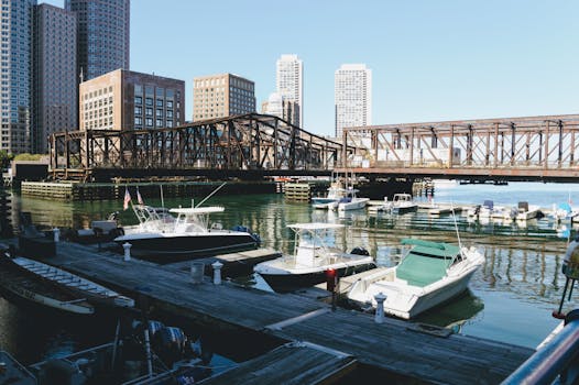 Scenic view of Boston's waterfront with boats, buildings, and a bridge on a sunny day.