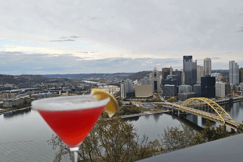 drink from the Grandview saloon on the patio with the pittsburgh skyline in the background.